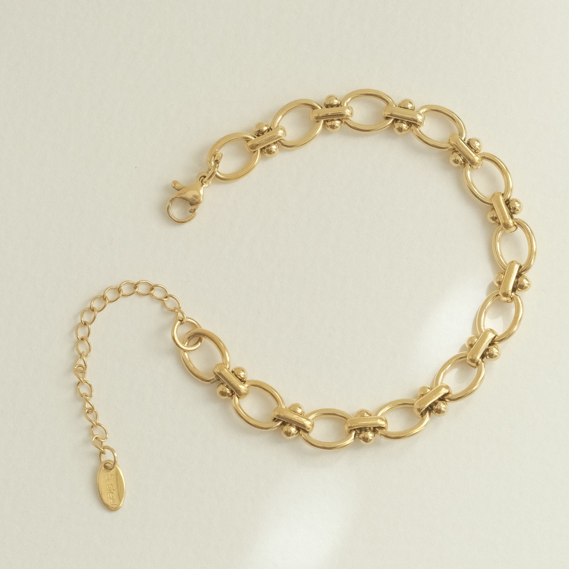 a gold chain bracelet with a gold charm