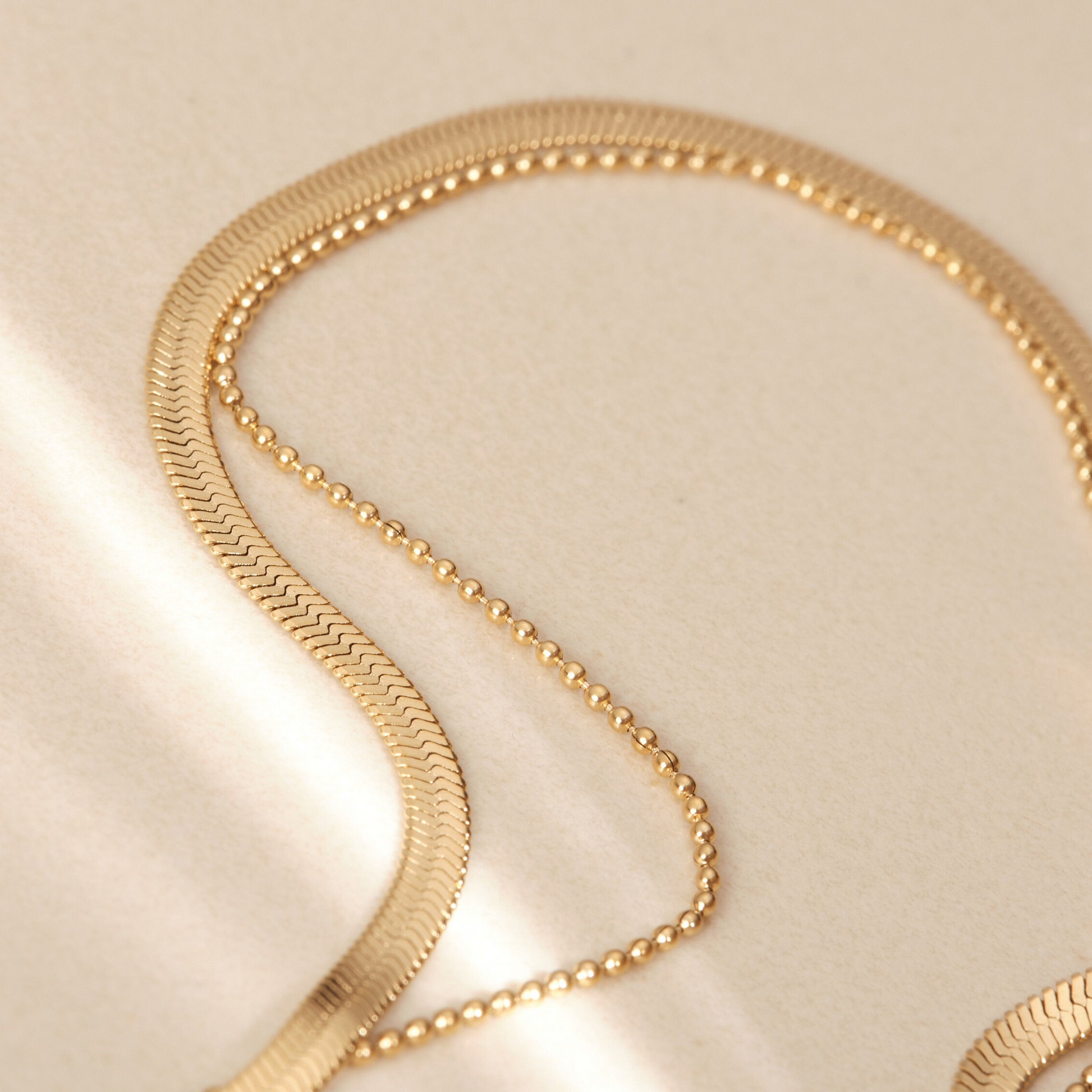 a close up of a gold necklace on a white surface