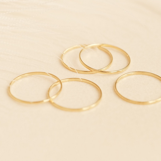 a set of four gold filled rings on a white surface