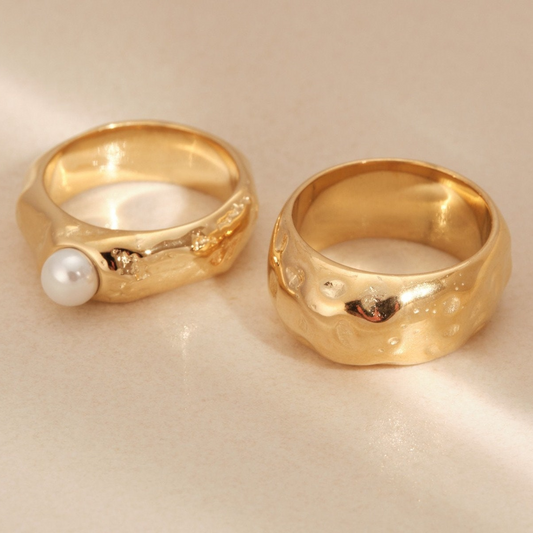 a pair of gold rings with a pearl