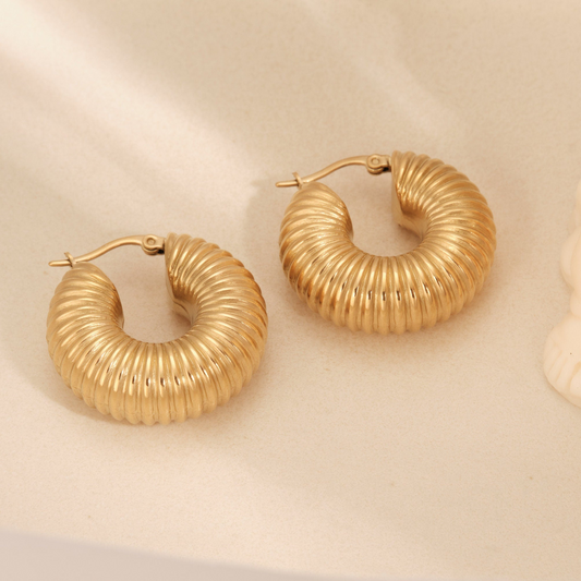 a pair of gold hoop earrings sitting on top of a table