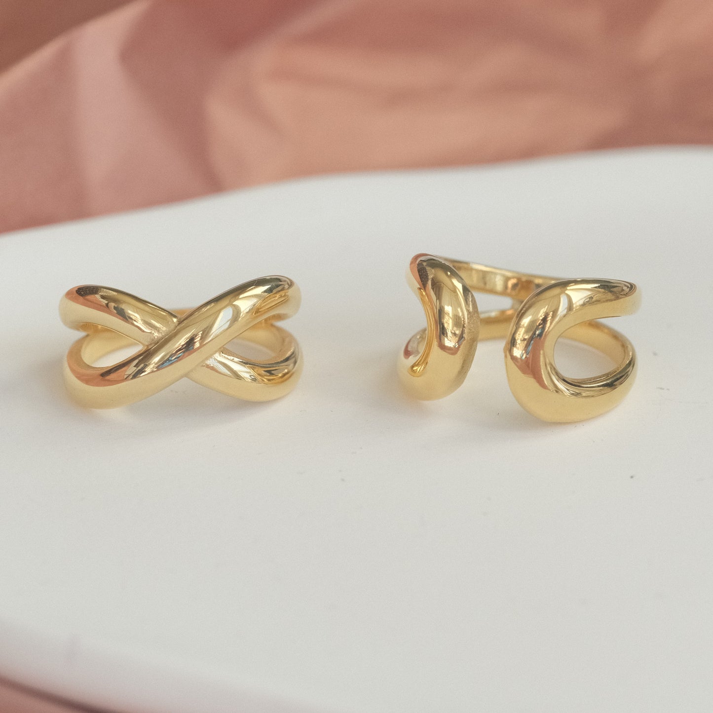 a pair of gold rings sitting on top of a white plate