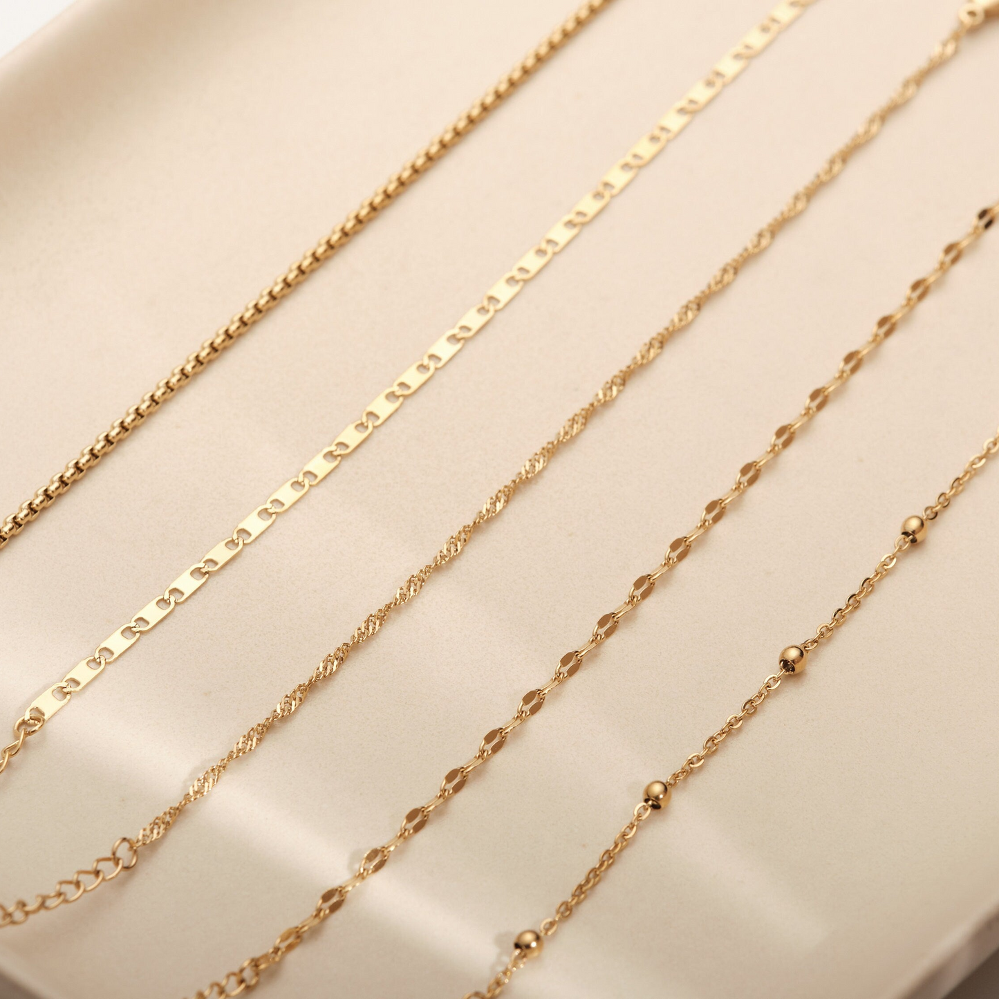 a row of gold necklaces sitting on top of a white box