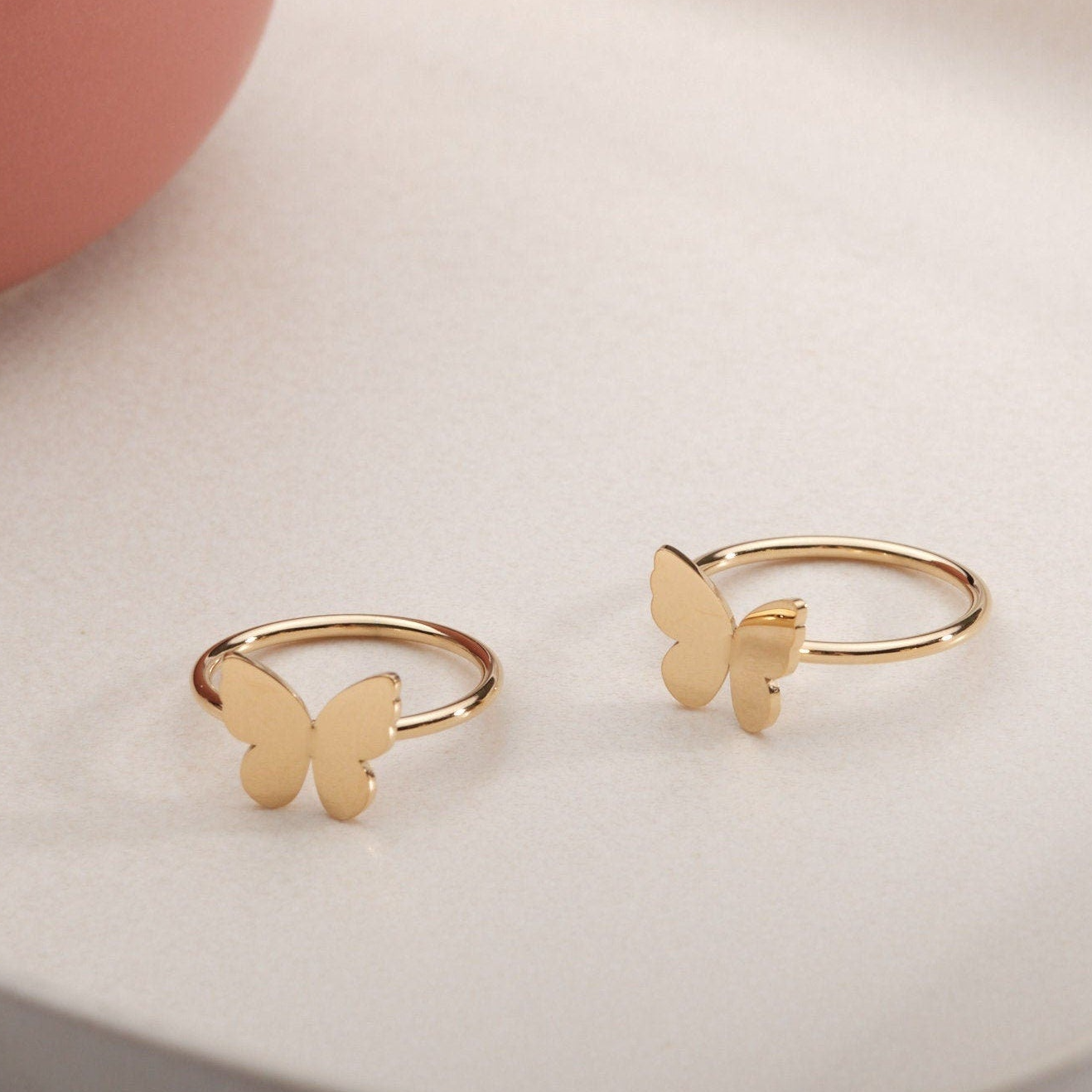 a pair of gold butterfly rings sitting on top of a table