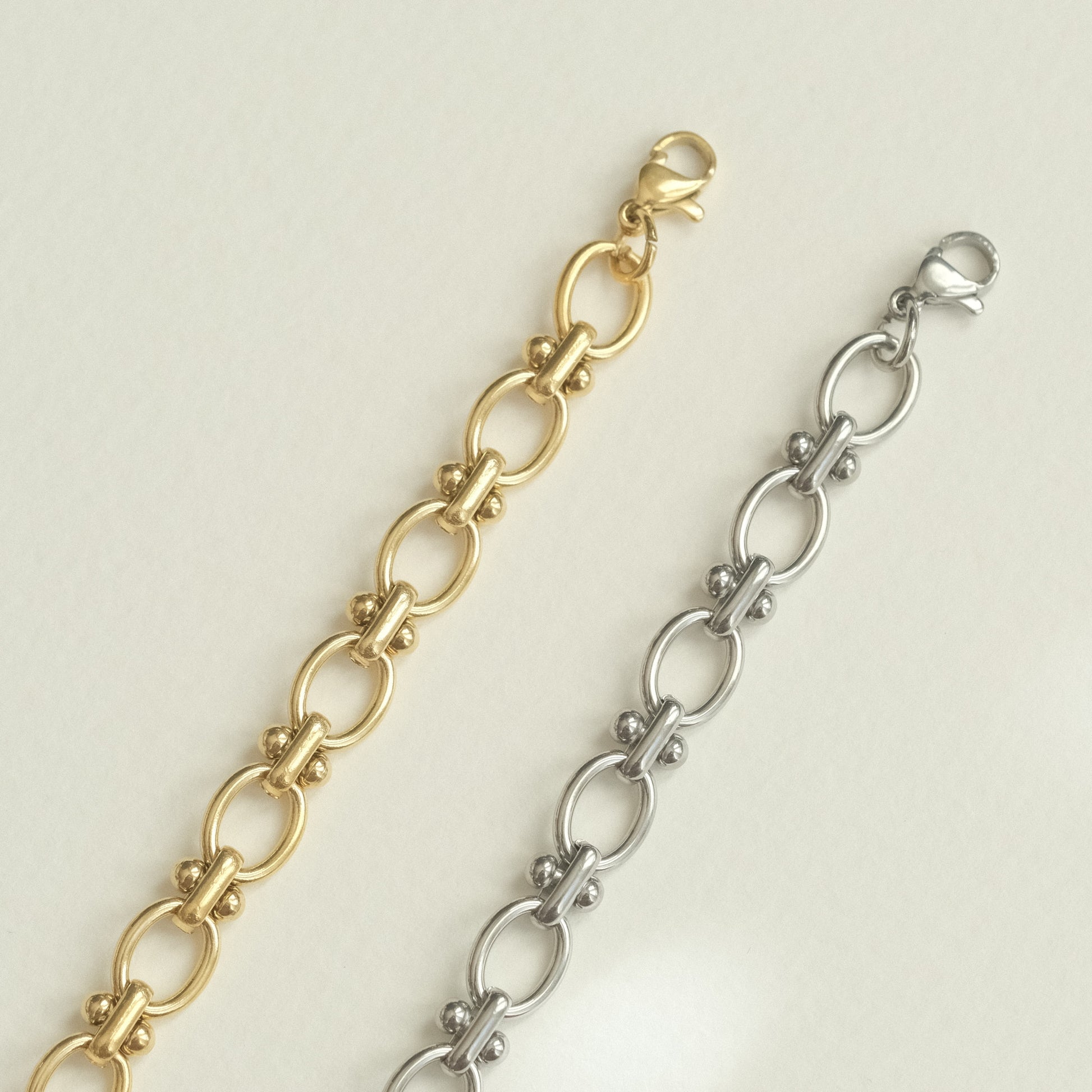 two gold and silver bracelets on a white surface