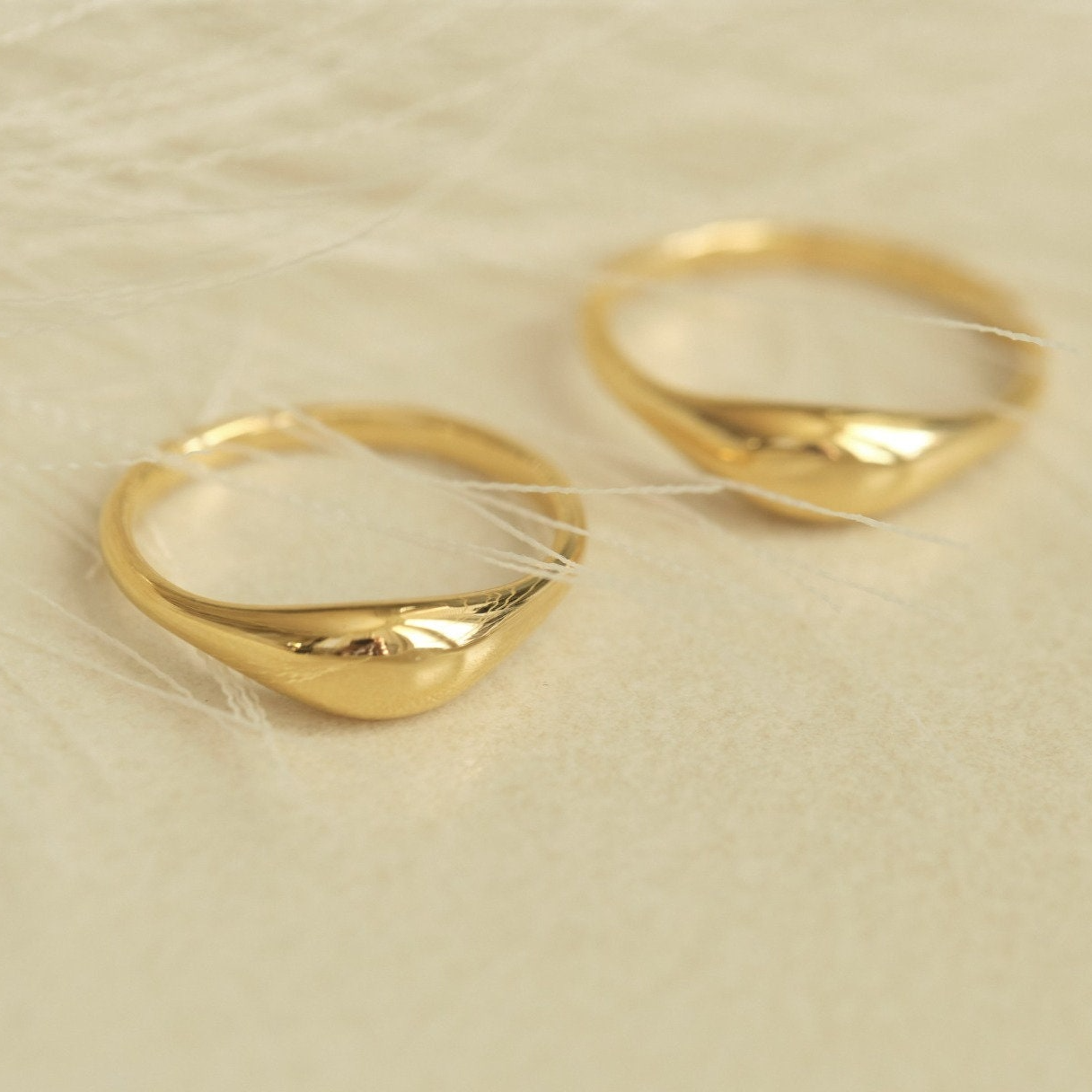 a pair of gold rings sitting on top of a white sheet