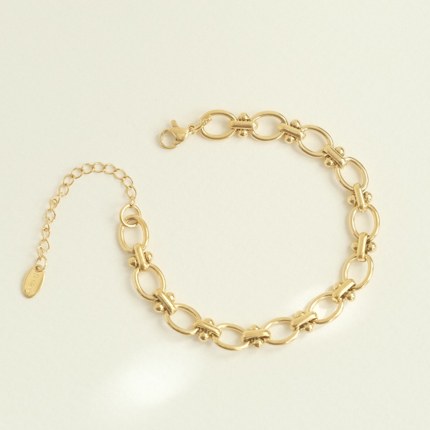 a gold chain bracelet on a white background