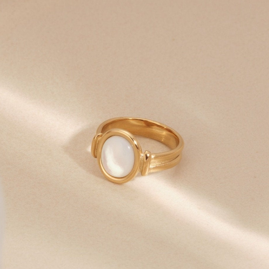 a gold ring with a white stone on it