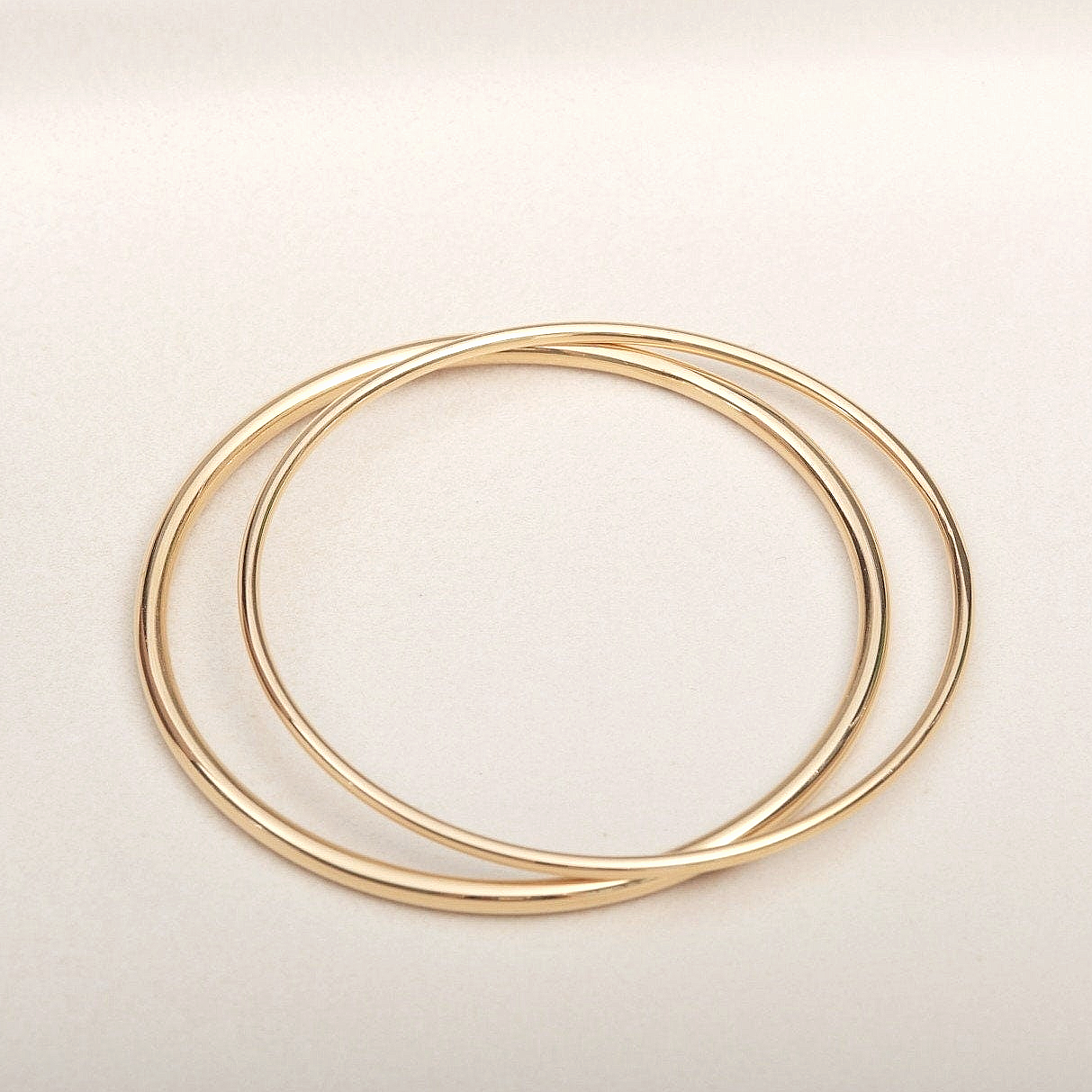 three gold rings on a white surface