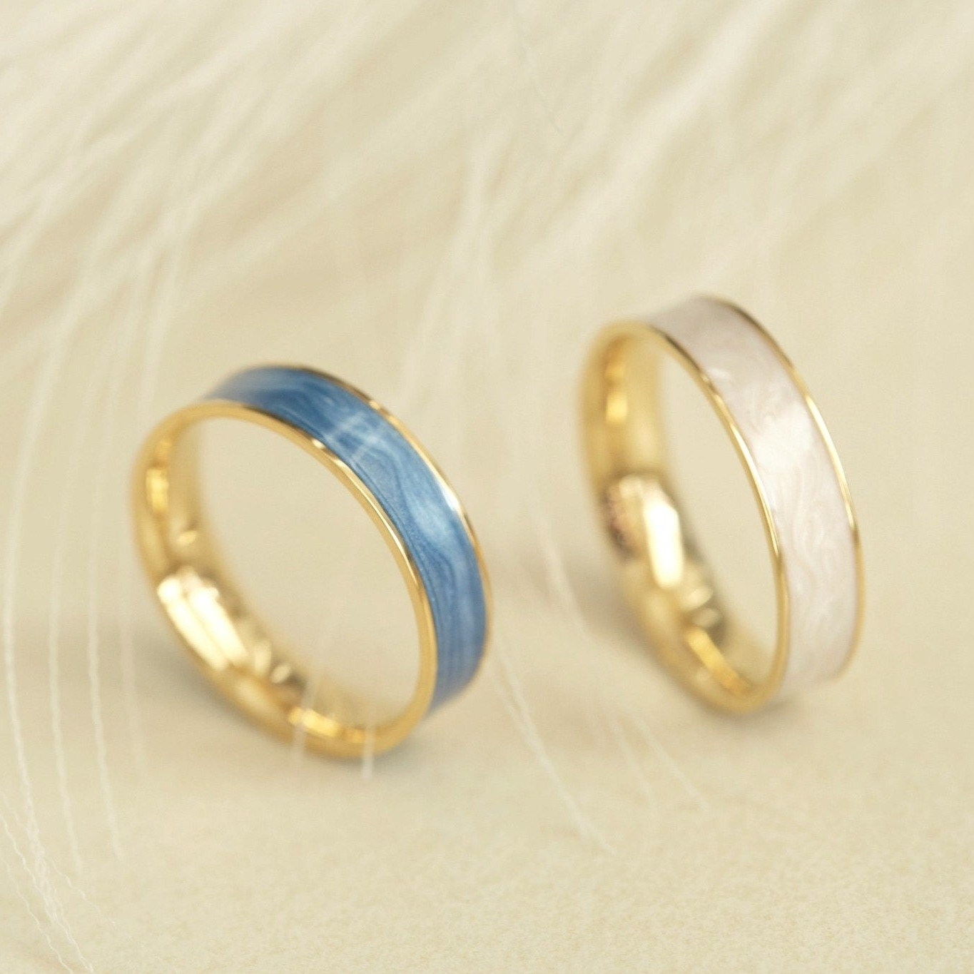 two wedding rings sitting on top of a feather