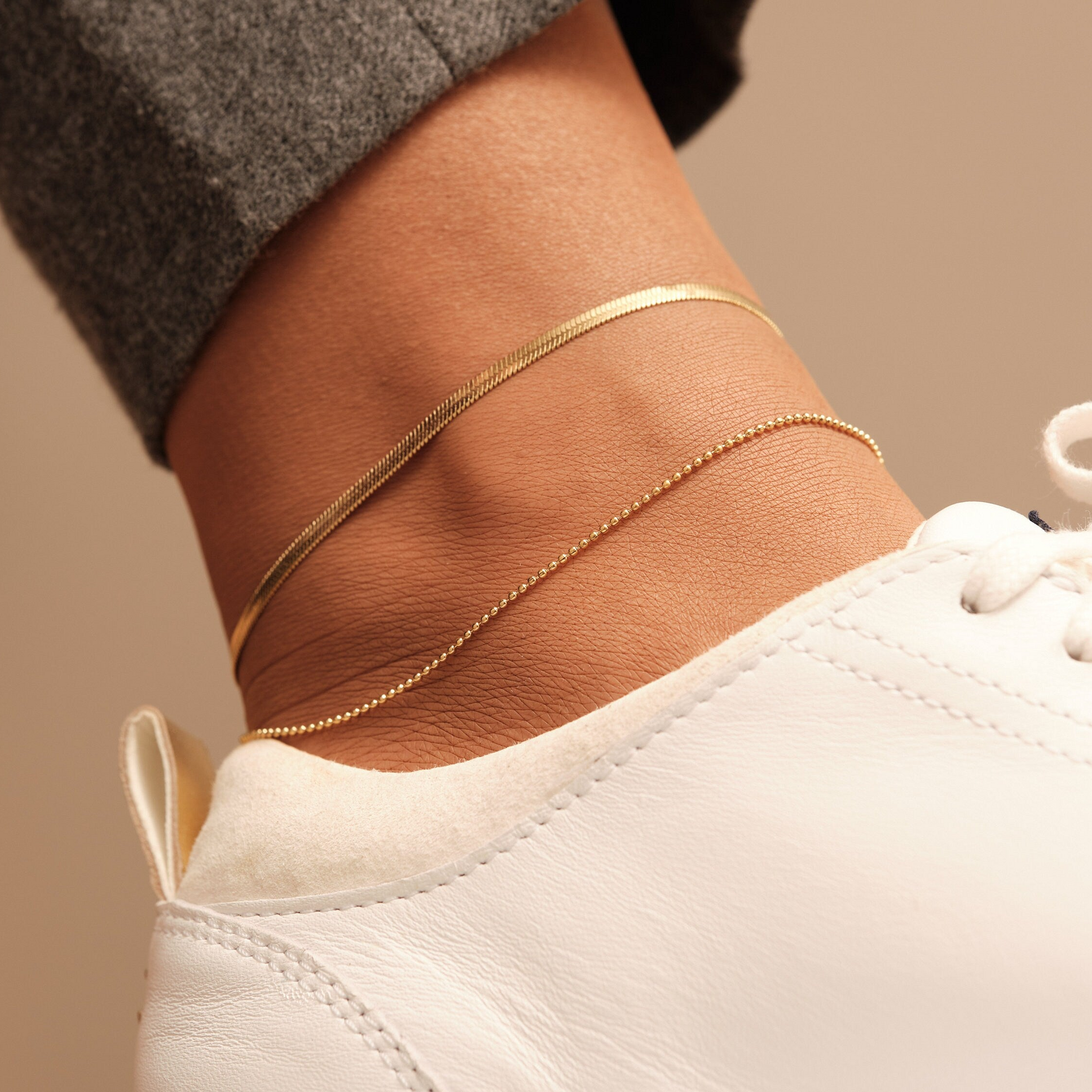 a woman's foot with a gold chain on her ankle