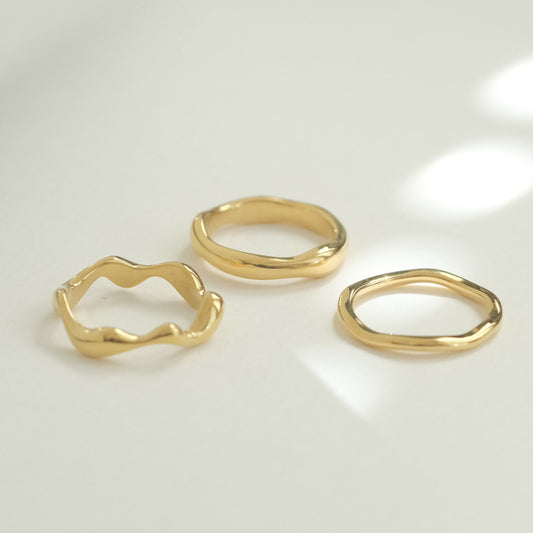 three gold rings on a white surface