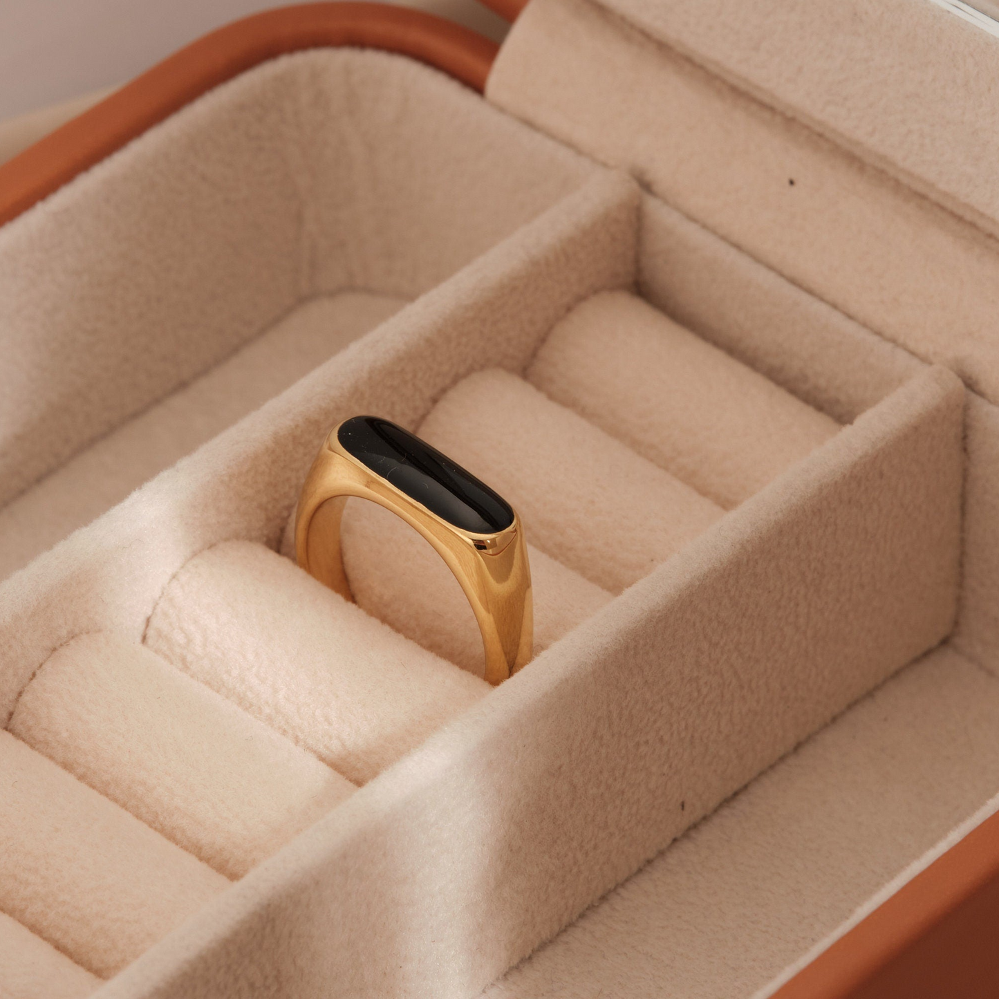 a gold ring with a black stone in a box