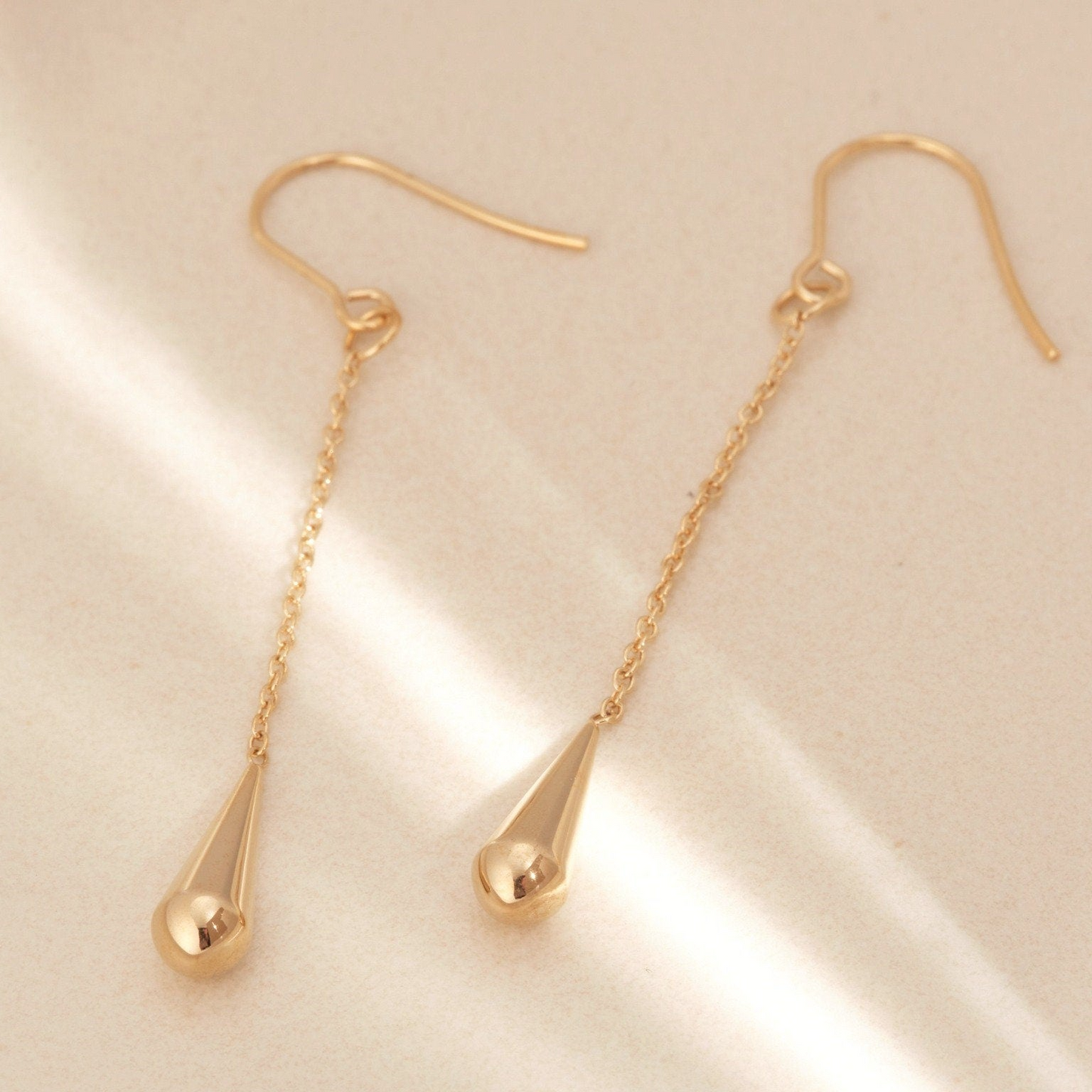 a pair of gold earrings on a white surface