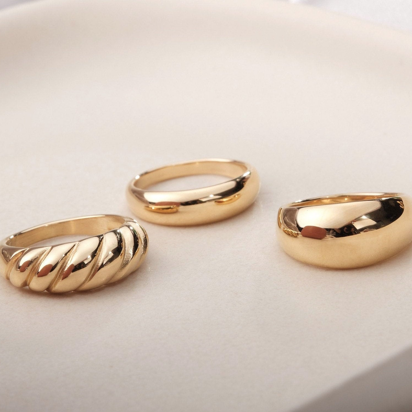 three gold rings sitting on top of a white surface