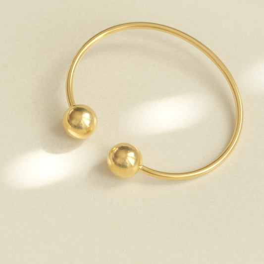 a gold ring with two balls on it